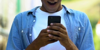 快乐的非裔美国少年在户外用智能手机聊天，来自爱人的信息