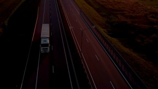 大型货车是移动的夕阳。空中拍摄的卡车在美丽的乡村道路在日落。鸟瞰图的半卡车在道路与日落的背景。视频素材模板下载