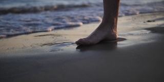 脚在海边的沙滩上留下痕迹，海水冲走了这些痕迹，近处，慢镜头