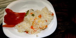厨房木板上的白盘子里放着热米饭、切好的西红柿和洋葱片。