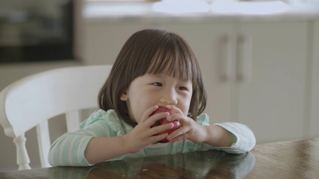 小女孩在家厨房吃苹果