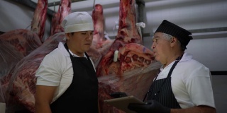 肉贩在肉柜中使用数字平板分析产品