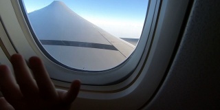 缩小镜头飞机机翼在天空与孩子的手在窗口。