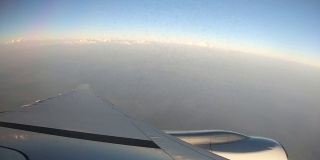 美丽的云带着飞机翅膀从窗口飞向天空。