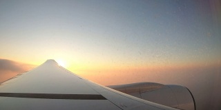 黄昏日落和美丽的云与飞机机翼在天空从窗口飞机。