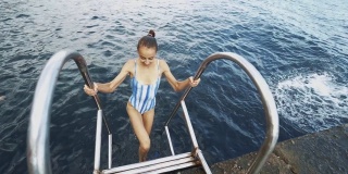 美丽苗条性感快乐的女人在蓝色泳衣放松，游泳和享受新鲜的水在山湖在炎热的阳光明媚的夏天
