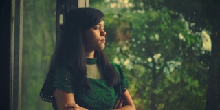 年轻女子沉思着，望着窗外的景色。