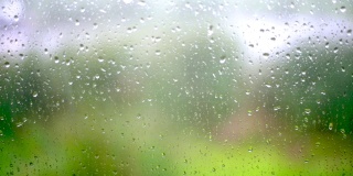 雨滴落在窗户玻璃上，背景是模糊的慢动作