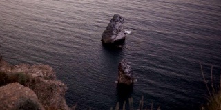 从悬崖上看大海或海水。鸟瞰图蓝色的水平静地与悬崖和岩石碰撞。海中孤独的岩石