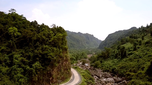 狭窄的柏油路沿着河边的山脚弯弯曲曲