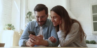 幸福的情侣使用智能手机玩手机游戏购物在应用程序