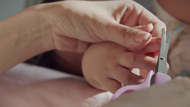 这是母亲在家里用指甲钳剪孩子的指甲的特写。婴儿身体护理概念。特写镜头前视图