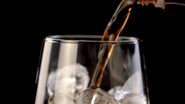 苏打(可乐)被倒进冰4K视频的普通玻璃杯