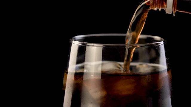 苏打(可乐)被倒进冰4K视频的普通玻璃杯