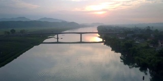 日落时分，飞摄像机从宽阔的河流上的高桥上移动