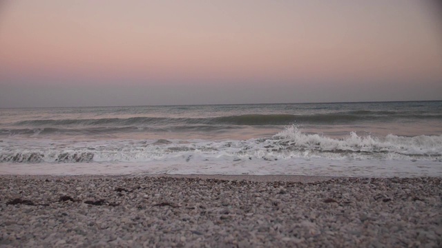 从海滩上的鹅卵石日落。海浪多雾的早晨。黎明前的阴霾。