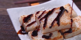 在餐厅将黑酱油倒在即食的美味萝卜糕上，这是中国传统的地方菜萝卜糕。