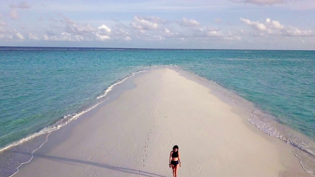 年轻的成年女子走在马尔代夫碧绿的沙滩上