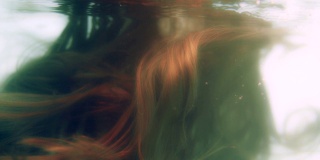 在水下，光在闪亮的棕色头发上移动