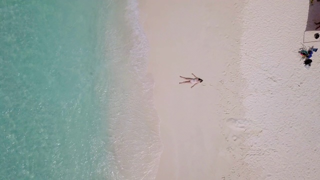 年轻的成年女子躺在天堂般的海滩上，背靠马尔代夫碧绿的海水
