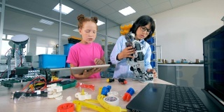 两个孩子在学校实验室里建造一个塑料机器人。技术教育的概念。