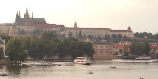 夜晚标志性的布拉格城堡和伏尔塔瓦河。人们享受着水上活动，并在河上游船经过