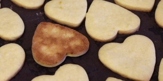 刚做好的饼干放在烤盘上冷却。心形和花朵形状的饼干。一个倒过来了，鲜红的一面可以看到。关闭了。