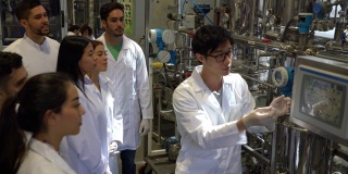 化工厂的工程师学生在他解释罐体和控制板的过程时注意大学伙伴