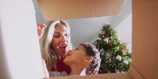母亲和儿子打开礼物在圣诞节早上从盒子里看