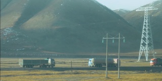 慢镜头:大型卡车在西藏平原上会合，运送货物。