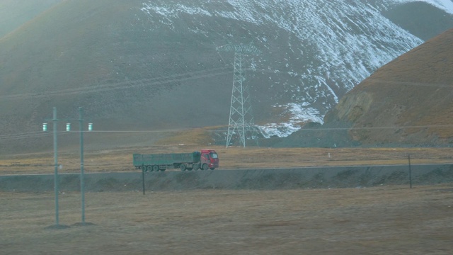 慢镜头:从移动的火车上看到一辆卡车在西藏运输货物。