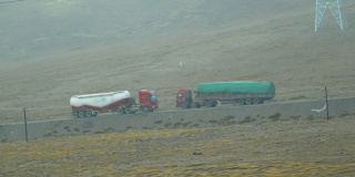 慢镜头:在浓雾弥漫的西藏，一辆货车拖着一个水箱行驶在一条路上。