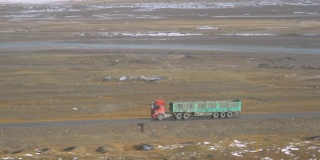 一辆红色货车带着空空的拖车沿着山涧行驶