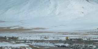 慢镜头:一辆卡车拖着一辆空拖车，后面是一座山的风景。