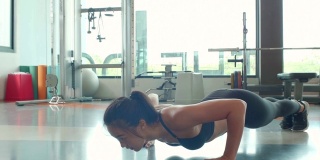 肖像亚洲健身妇女做推举运动在体育健身房的背景。人的生活方式和运动理念。在地板上保持身体平衡的女运动员。女孩在运动服装
