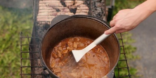 在大铁锅里准备菜，用红洋葱和肉等组成