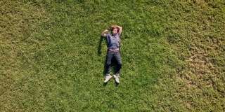 十几岁的男孩躺在草地上玩他的智能手机