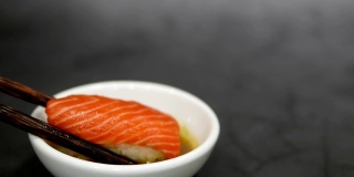 手拿寿司用木筷子蘸芥末和日式酱油