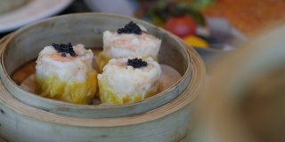 中国饺子烧卖与鱼子酱顶部在圆形的竹蒸笼。豪华餐厅菜单,