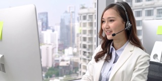 亚洲女商人在呼叫中心城市办公室通过耳机交谈