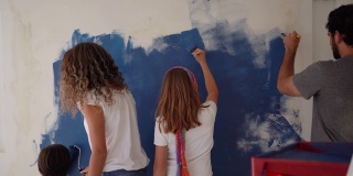 后视图拉丁美洲年轻的家庭油漆墙壁与蓝色在家里