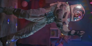 在大学宿舍的化妆舞会上:有趣的家伙穿着太空服跳舞，跳着时髦的机器人现代舞。美丽的女孩，男孩跳舞。垂直屏幕方向的视频片段9:16