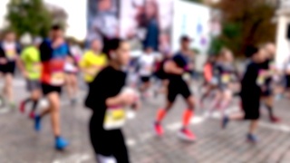 在慈善城市马拉松赛期间，许多人在城市街道上跑步的模糊剪影的特写。参赛者运动员在城市的街道上跑很长的距离。慢动作。视频素材模板下载