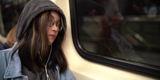 一个年轻的亚洲女人睡在地铁里