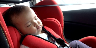 在汽车安全座椅上睡觉的婴儿。亚洲女孩在开车时在汽车座椅上打盹。