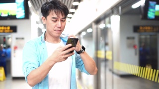 一名亚洲男子在地铁站使用手机视频素材模板下载