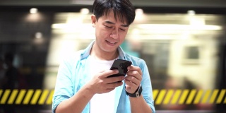 一名亚洲男子在地铁站使用手机