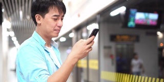一名亚洲男子在地铁站使用手机