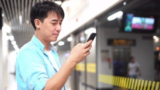一名亚洲男子在地铁站使用手机视频素材模板下载