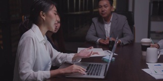 4K分辨率亚洲女商人晚上在办公室开会。商业伙伴讨论和头脑风暴计划。投资财务分析理念，亚洲商业室内生活方式。亚洲同事和团队合作理念，工作到深夜的理念